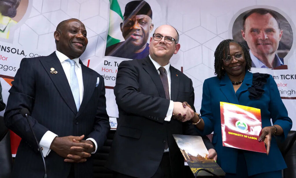 University of Birmingham Provost Professor Nick Vaughan-Williams shaking hands with UNILAG Vice-Chancellor Professor Folasade Ogunsola as they exchange partnership documents, with Education Minister Tunji Alausa